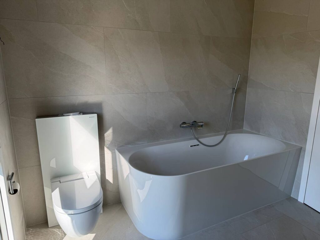 Badewanne vor beige gefliesten Wänden